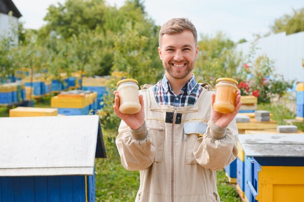 Photo beekeeper with honey in jars at apiary