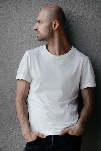 Foto beeld van een knappe kale man in een wit t-shirt op een grijze achtergrond