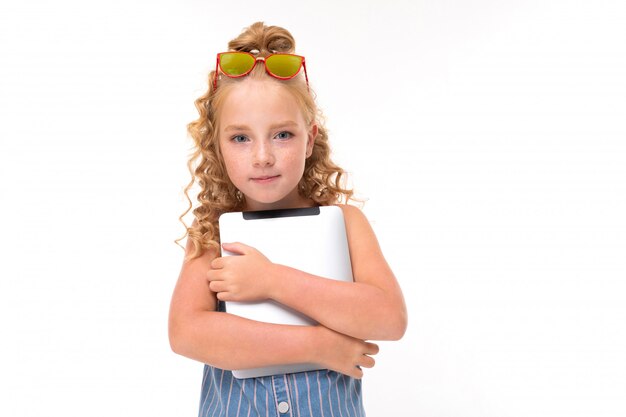 Beeld van gelukkig kind met eerlijk rood krullend haar met een tablet die op witte achtergrond wordt geïsoleerd