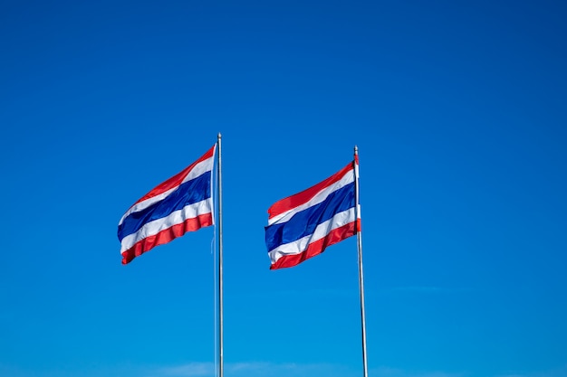 Beeld van het zwaaien van 2 Thaise vlag van Thailand met blauwe hemelachtergrond.