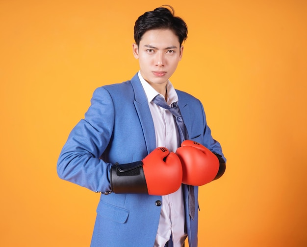 Beeld van jonge Aziatische woedezakenman met bokshandschoen