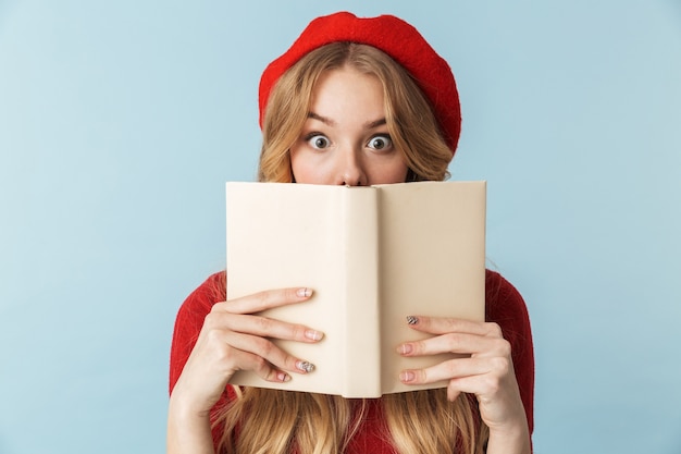 Beeld van slimme blonde vrouwen20s die het rode geïsoleerde boek van de baretlezing dragen