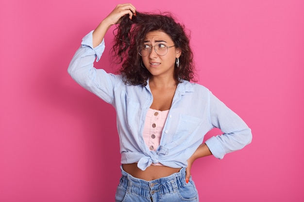 Beeld van verward mooi jong donkerbruin vrouwen golvend haar dat haar haar bekijkt