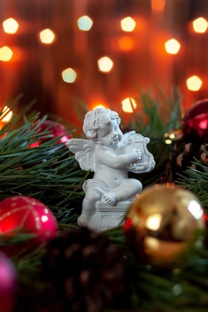 Beeldje van een engel die harp speelt op een tak van een kerstboom op een achtergrond van bokeh