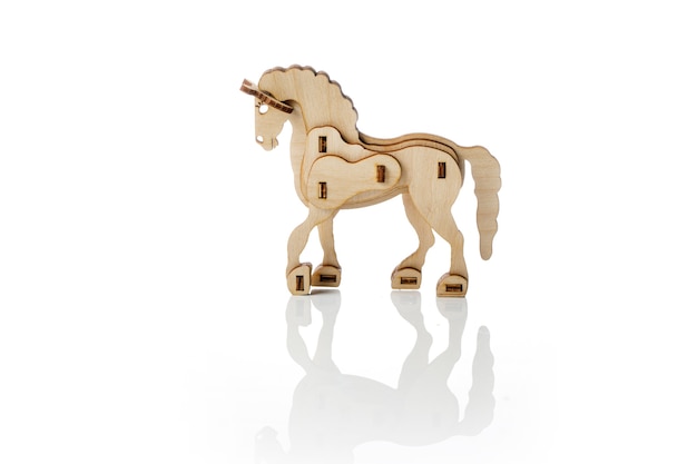 Beeldje van een speelgoed houten paard op een witte achtergrond met reflectie.
