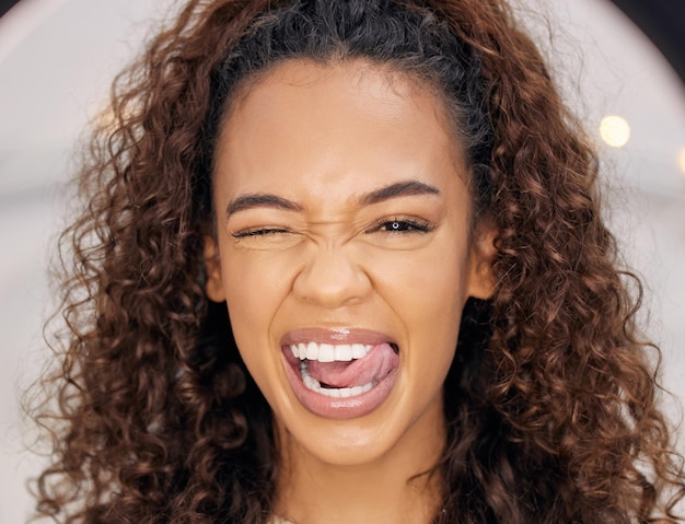 Been good way too long. Portrait of a beautiful young woman playfully posing with her tongue between her teeth while standing indoors.