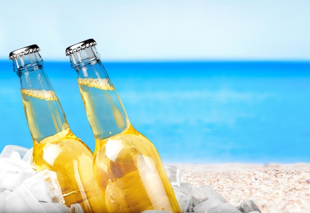 Photo beer bottles in ice on beach background