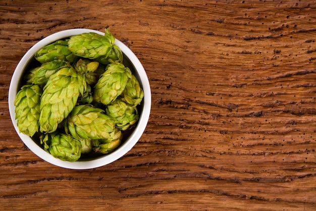 Beer brewing ingredients Hop cones in white bowl on wooden background. Beer brewery concept.