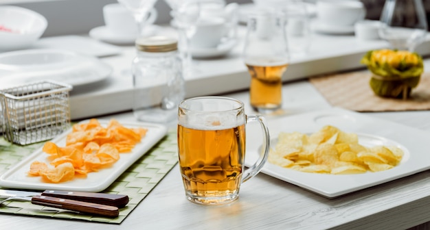 Birra e patatine fritte sul grande tavolo bianco