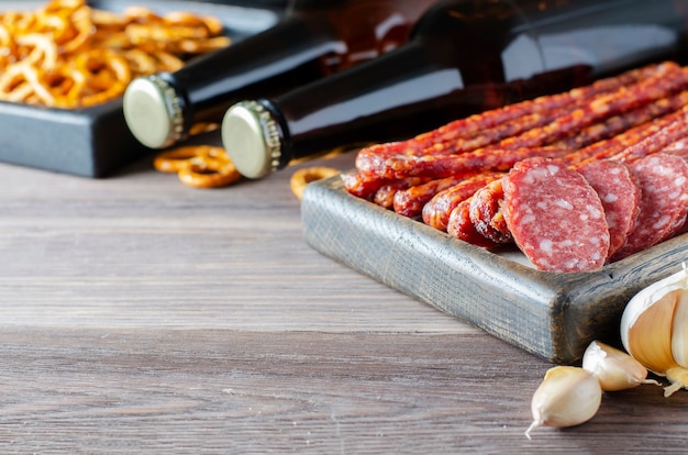 Birra in bottiglie di vetro scuro, snack salati per birra, salsiccia