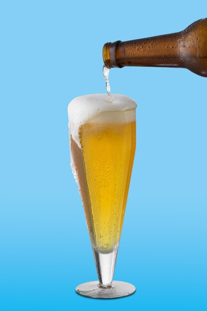 Foto bicchiere di birra bottiglia di birra riempie il bicchiere su sfondo blu