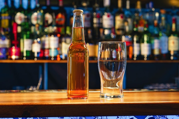 Beer glass and bottle on wooden countertop in a pub