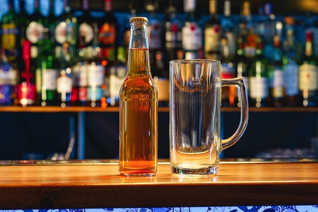 Beer glass and bottle on wooden countertop in a pub