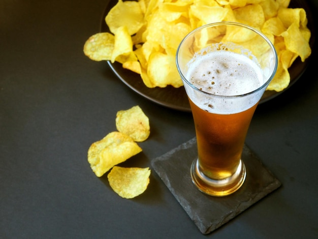 Foto birra in un bicchiere e patatine fritte su un piatto