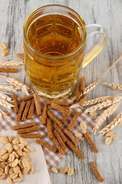 Beer in glass crunches and nuts on napkin on wooden table