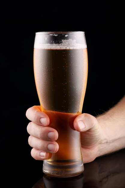 Beer in a glass in hand on black surface