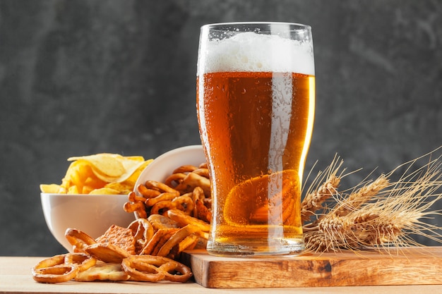 Beer glass with bretzel and dried sausages snacks close up