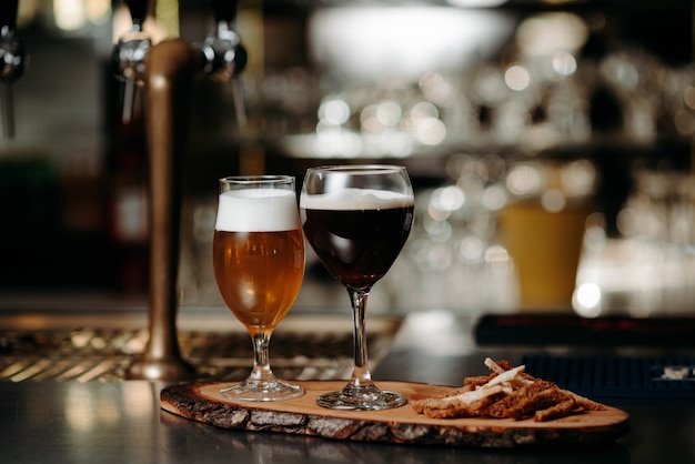 Foto birra in bicchieri su una tavola di legno con crostini di pane