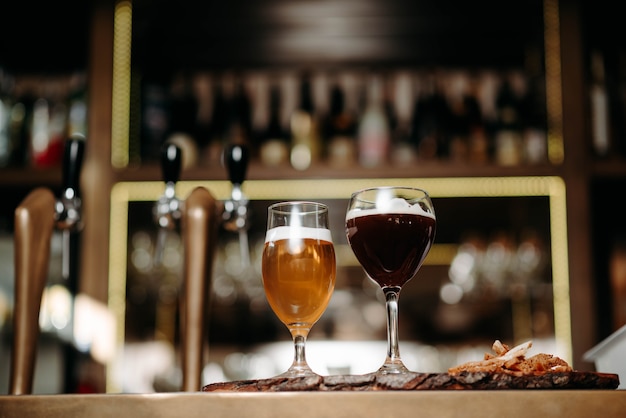 Foto birra in bicchieri su una tavola di legno con crostini di pane