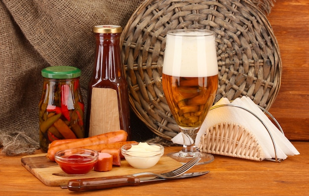 Beer and grilled sausages on wooden table on sackcloth