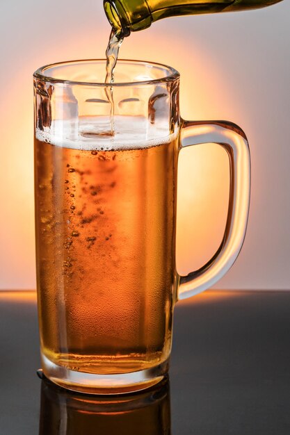 Beer is poured from a bottle in a glass mug, close-up