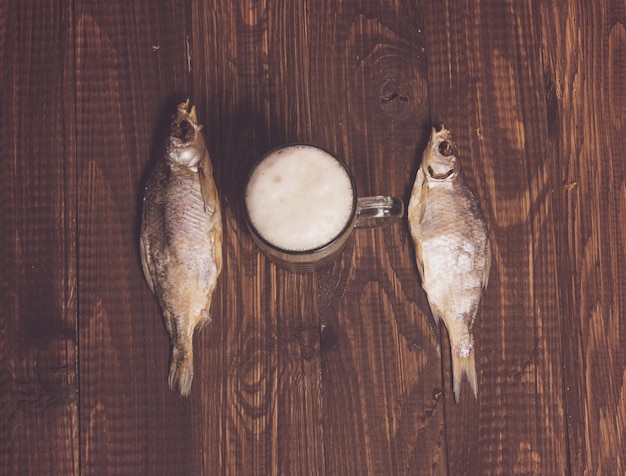 The beer is between two fishes on the wood table