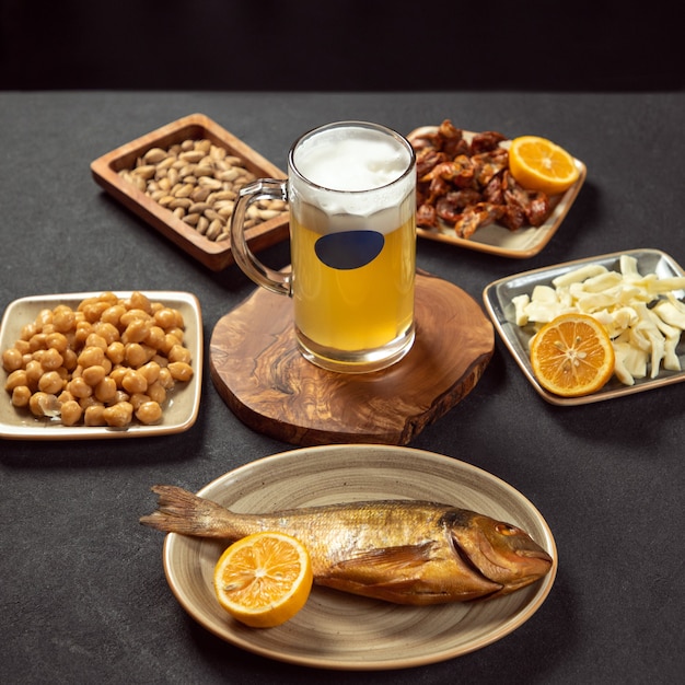 Boccale di birra con pesce alla griglia, piselli, snack al formaggio