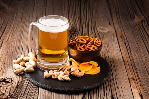 Photo beer mug with pistachio and snacks on wooden board