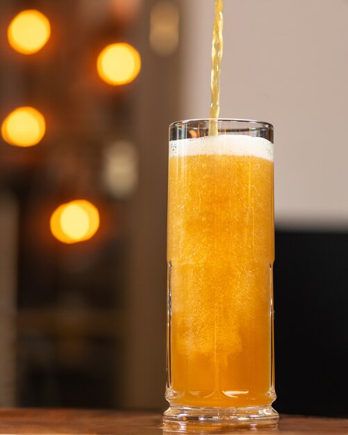 Versare la birra, riempire la tazza, vetro con sfondo bokeh