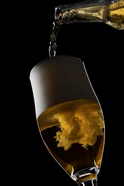 A beer pouring in a glass on a black background.