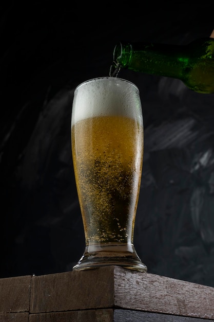 Beer pouring into cup in a bar Wooden desk and grey background