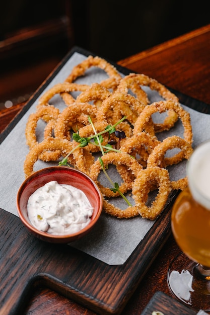 Beer set appetizers fried onion rings with tartar sauce and glass of beer