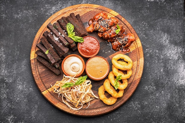 Spuntino alla birra su tavola di legno anelli di cipolla crostini calamari ali di pollo alla griglia e salse