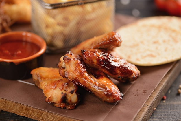 Beer snacks. Fried chicken wings, french fries, onion rings, cheese in batter and dried meat. On a wooden board