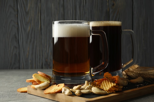 Birra e snack sul tavolo grigio contro il legno