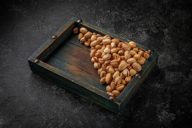 Photo beer snacks pistachio nuts in a wooden box on a dark table