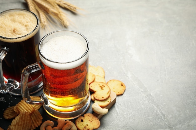 Birra, grano e spuntini sulla tavola grigia