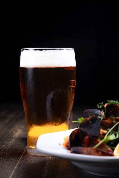 Foto birra con cozze in salsa di pomodoro con microgreens e limone su fondo di legno