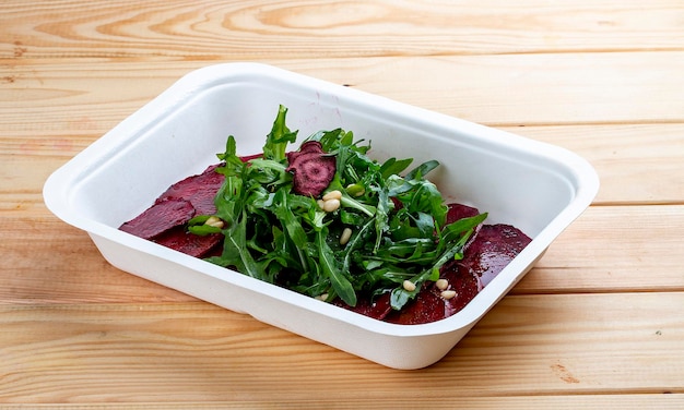 Beet carpaccio arugula en noten Vegetarisch eten Takeaway eten op een houten achtergrond