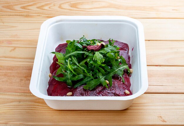 Foto beet carpaccio arugula en noten vegetarisch eten takeaway eten op een houten achtergrond