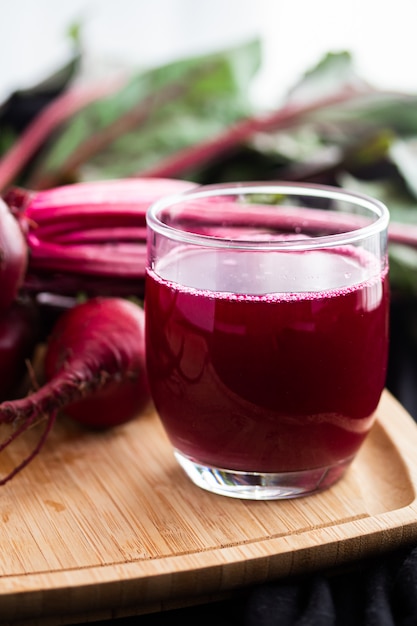 Beet juice in a glass on a wooden board, with fresh beets