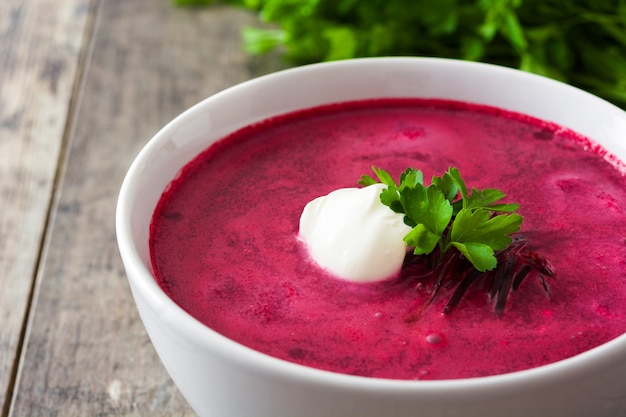 Beet soup in white bowl on wooden table