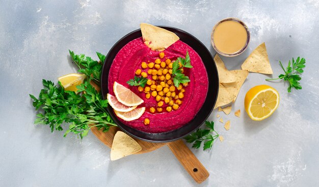 Beetroot hummus in plate with chickpeas and pita bread