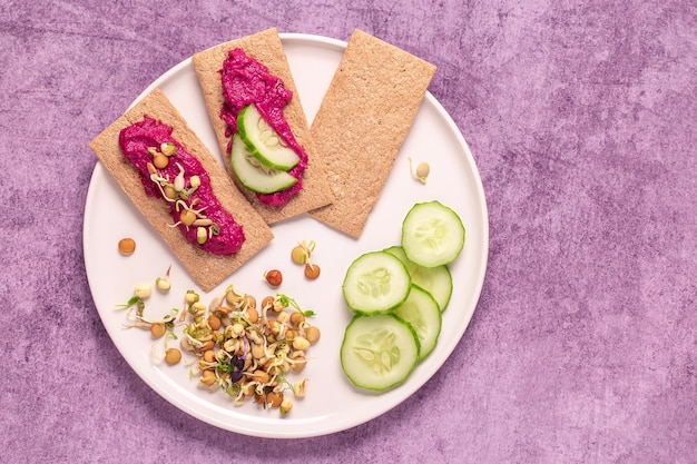 Beetroot hummus sprouted grains cucumber and whole grain crisps