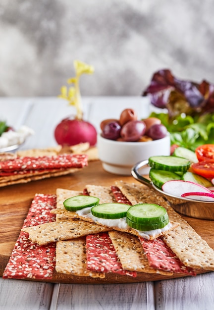 Cracker della farina di segale e della barbabietola con le verdure per produrre gli spuntini su una parete di legno. vegetarianismo e alimentazione sana.