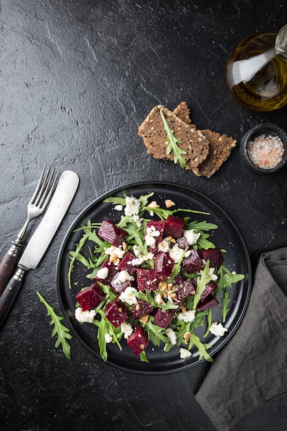 Beetroot salad with blue cheese, arugula and walnut in a black plate on stone background, top view