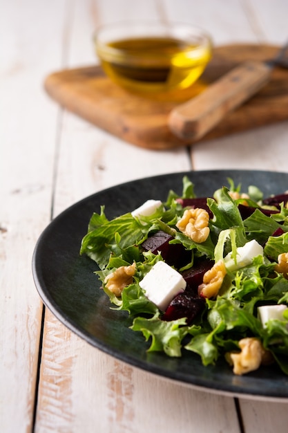 Салат из свеклы с сыром фета, листьями салата и грецкими орехами на деревенском деревянном столе