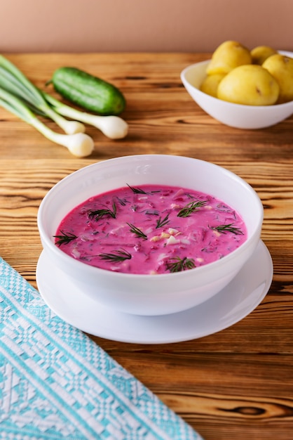 Beetroot with egg, herbs and potatoes on a wooden table. Russian traditional cold soup.