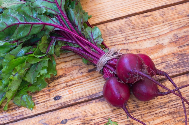 Beets with stems and leaves on a wooden table.