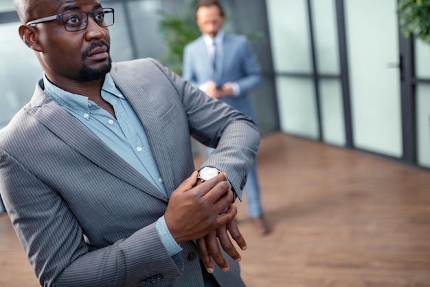 Before important meeting. Dark-eyed businessman in glasses feeling concerned before important meeting